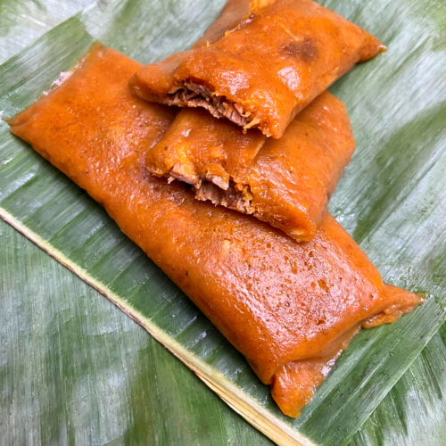 Puerto Rican pasteles wrapped in banana leaves, sliced open